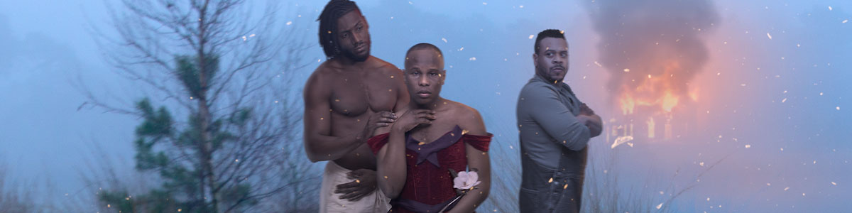 A Black man in a red dress holding a magnolia blossom, stands in a foggy swamp with a taller, shirtless Black man on one side of him and a disapproving Black man with his back turned on the other side. In the distance, a house is on fire.